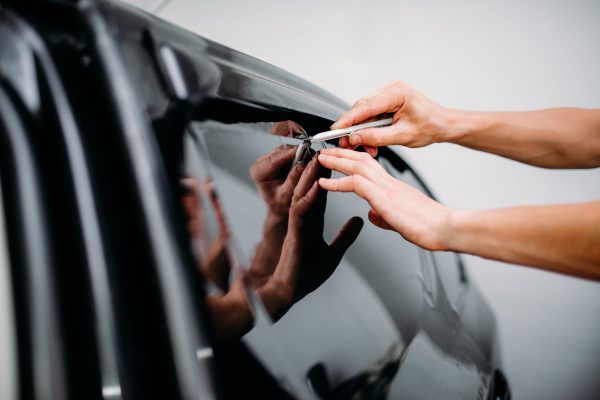 Male specialist work with car, tinting film installation process, tinted auto glass installing procedure